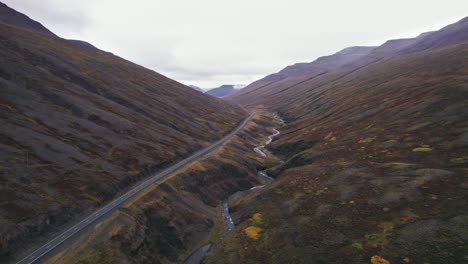 aerial: carretera vacía sin coches a lo largo de la carretera de circunvalación de islandia que es una carretera panorámica a través de una pintoresca zona remota del fiordo que conduce a la niebla y la neblina en la distancia