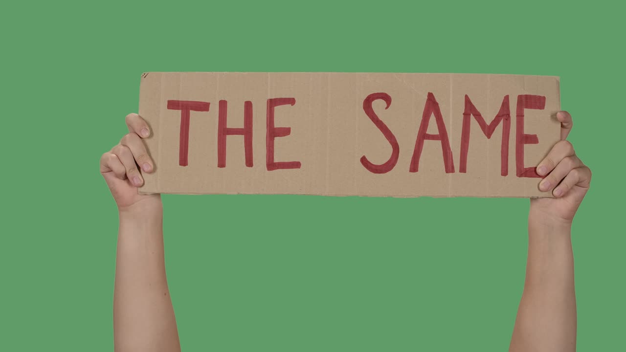 Protesting poster with inscription THE SAME. Background to illustrate the movement for the freedom of human rights. Female hands holding poster green screen, chroma key. Close up. Slow motion