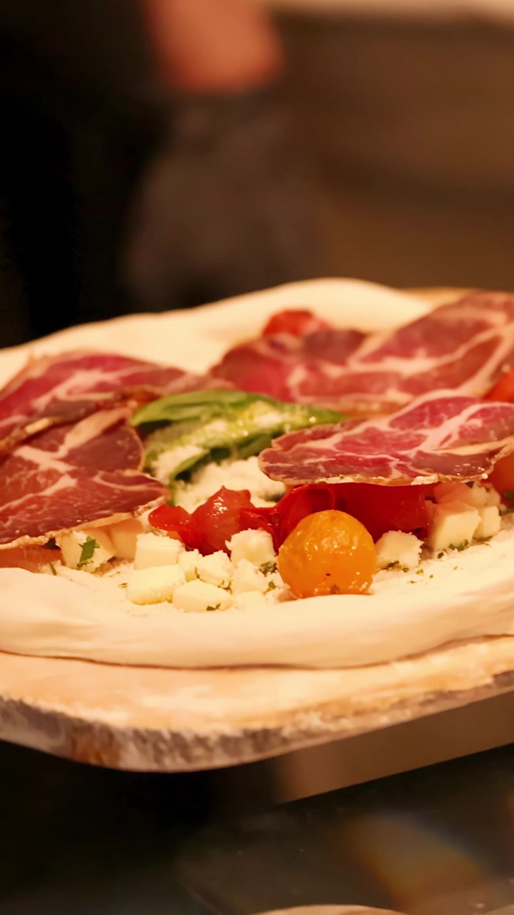 Chef che prepara pizza gourmet con salumi e verdure fresche