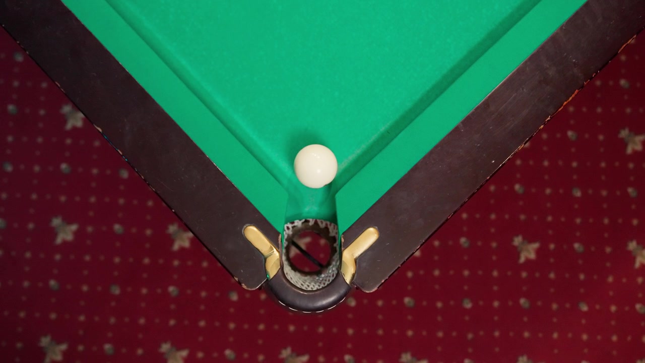 Witte poolbal verdwijnt in de hoekpocket op een groene tafel