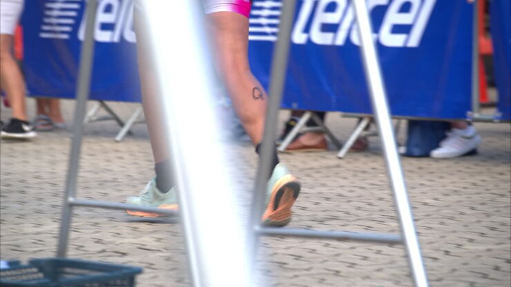 Rallentatore delle gambe di un'atleta che inizia la fase di corsa in un triathlon, all'interno della zona di transizione.