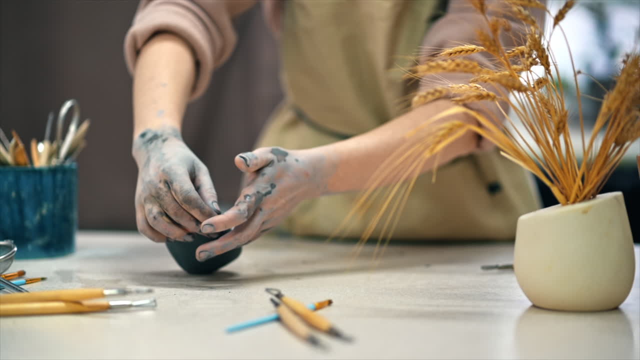 The master of sculpting pottery working in a studio. Kneading a piece of clay with her hands. Tools on the table. Slow motion