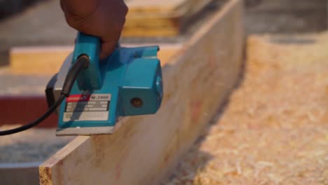 working carpenter to smoothen the plank using planer machine