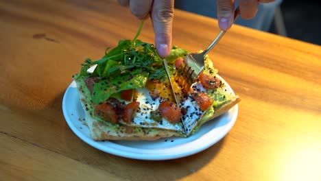 tostadas de aguacate comiendo en cámara lenta cortando y goteando yema