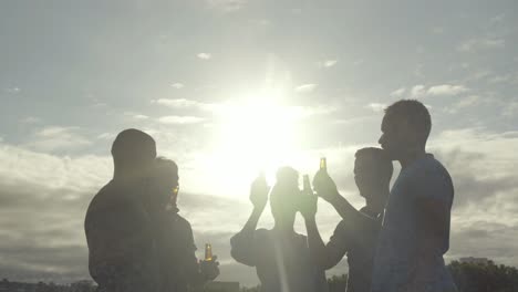 Fröhliche-Freunde-Jubeln-Mit-Bier-Vor-Dem-Sonnenuntergangshimmel