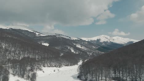 A-drone-shot-of-forest-mountains-with-snow,-warm-weather,-flying-above-the-snowboard-area,-4K-video,-European-winter-nature