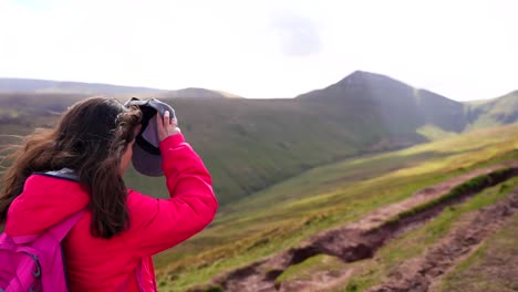 una mujer mochilera se pone una gorra y camina hacia la montaña pen y fan en un día soleado