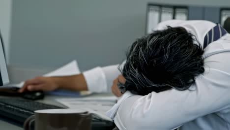 exhausted businessman sleeping at his desk in the office, showcasing the toll of long hours and high stress. overworked and fatigued, he drifts into a much needed nap amidst deadlines and pressure