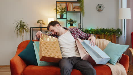 young happy man shopaholic consumer came back home after shopping sale with purchase bags orders