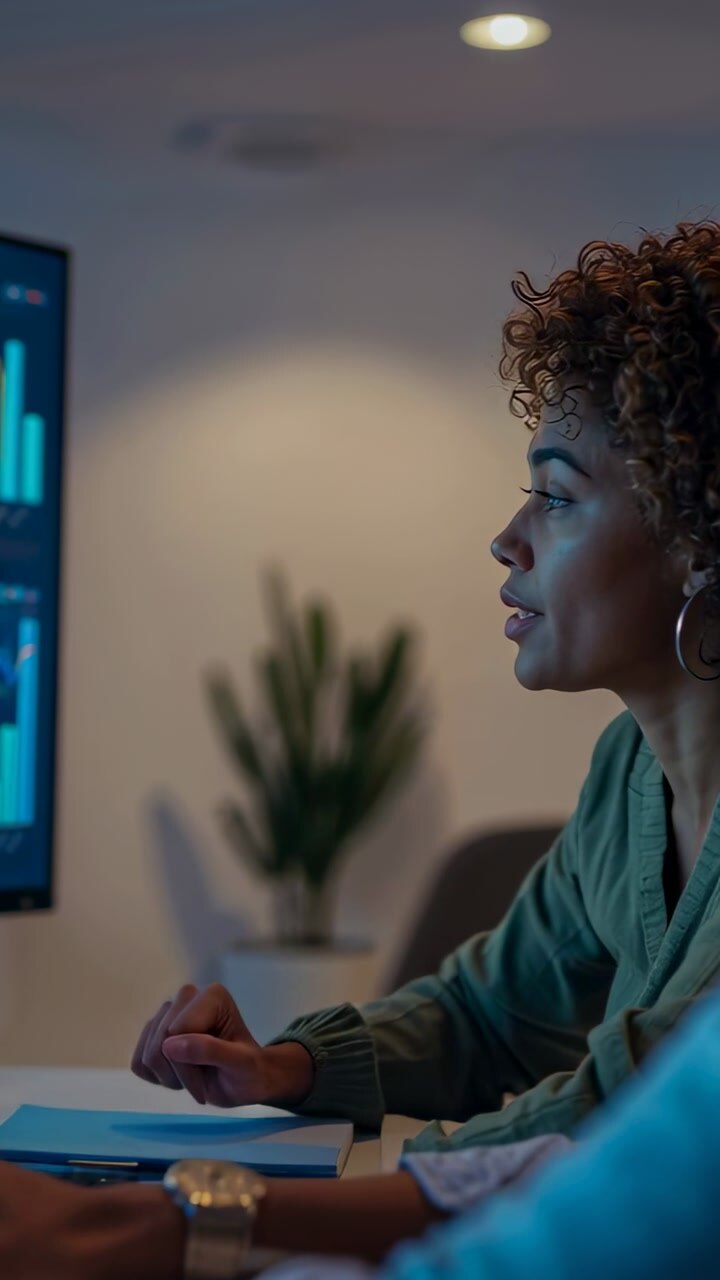 Analyst leaning to monitor, pointing at charts as arm entering, animated cues showing data insight