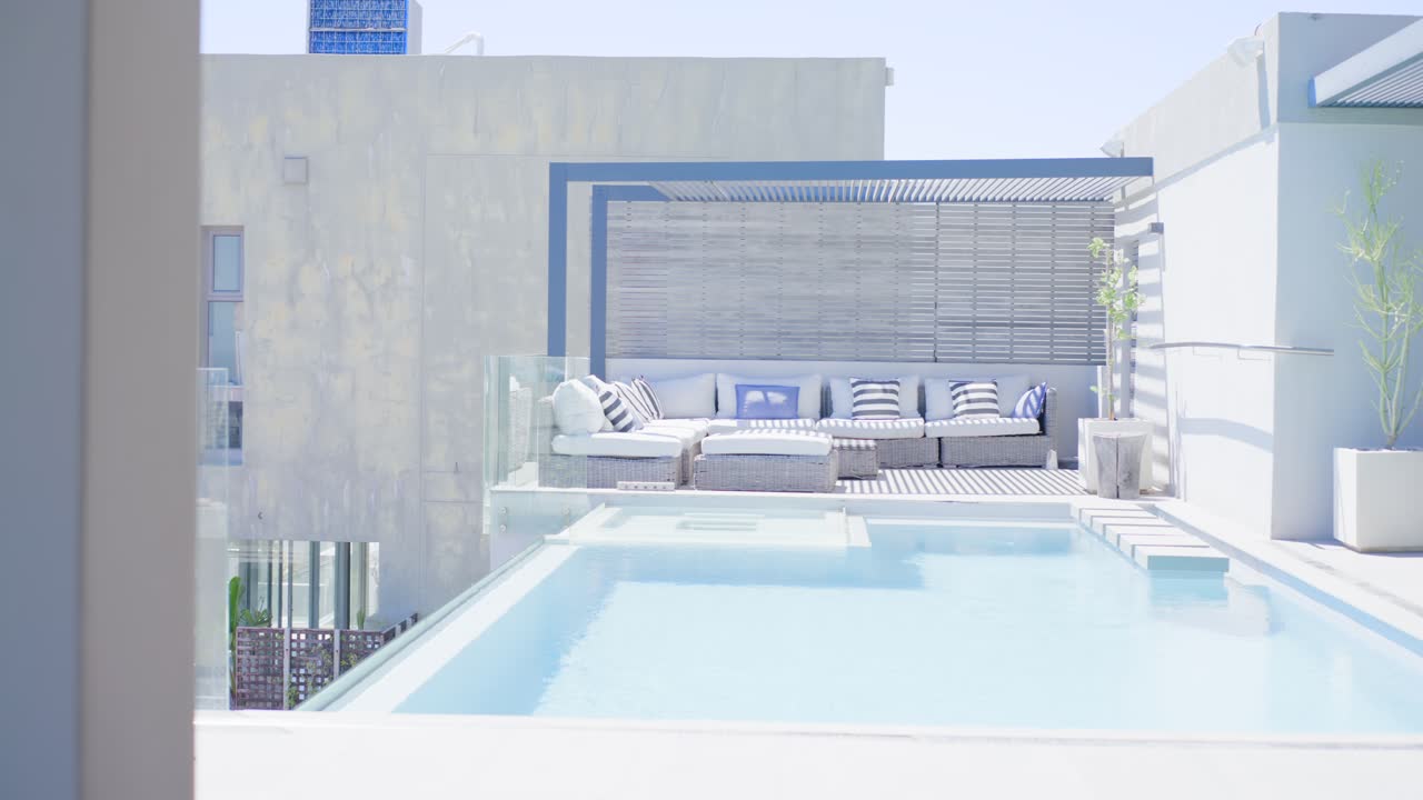 Camera panning from left, revealing rooftop pool with shallow ledge, steps, sectional sofa
