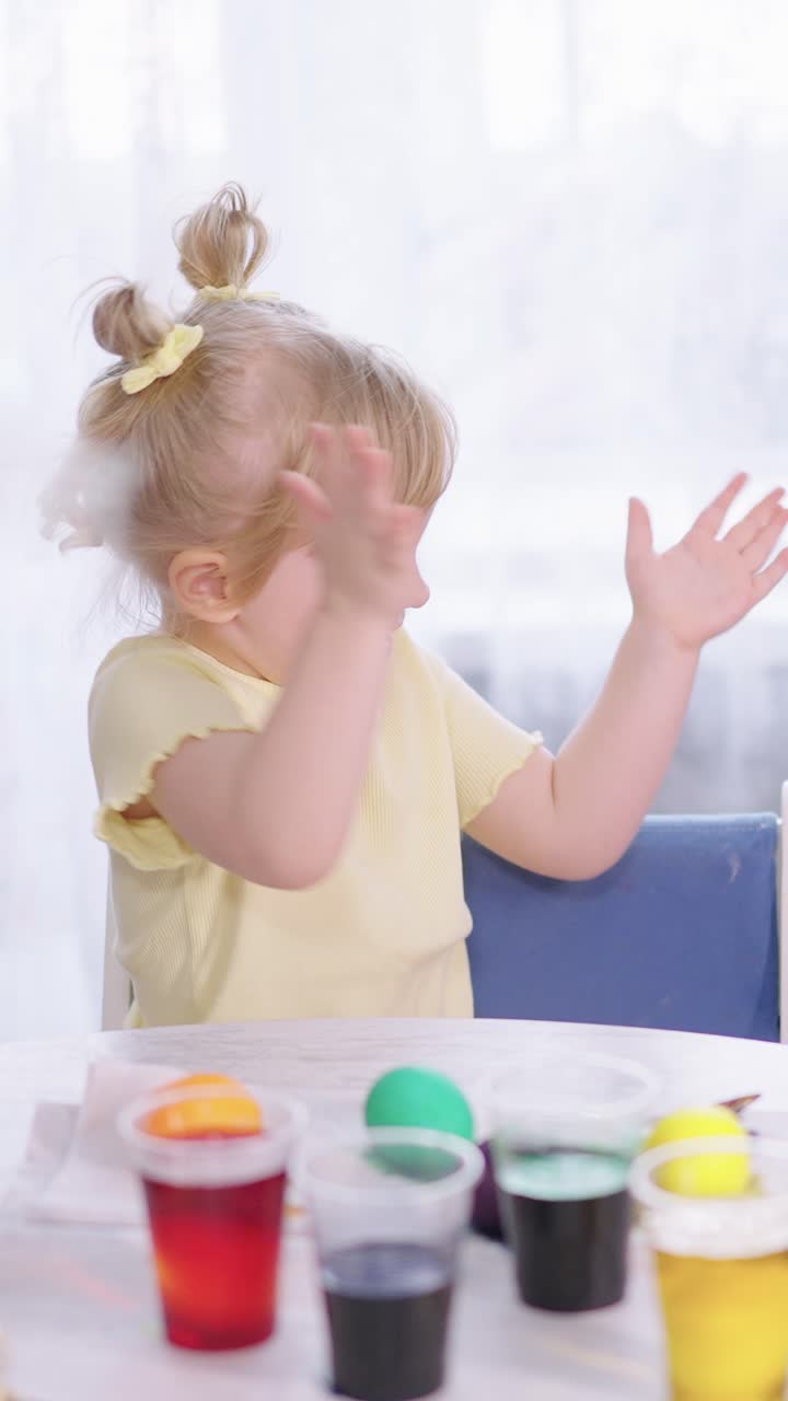 Happy Toddler Girl Clapping Hands While Painting Easter Eggs