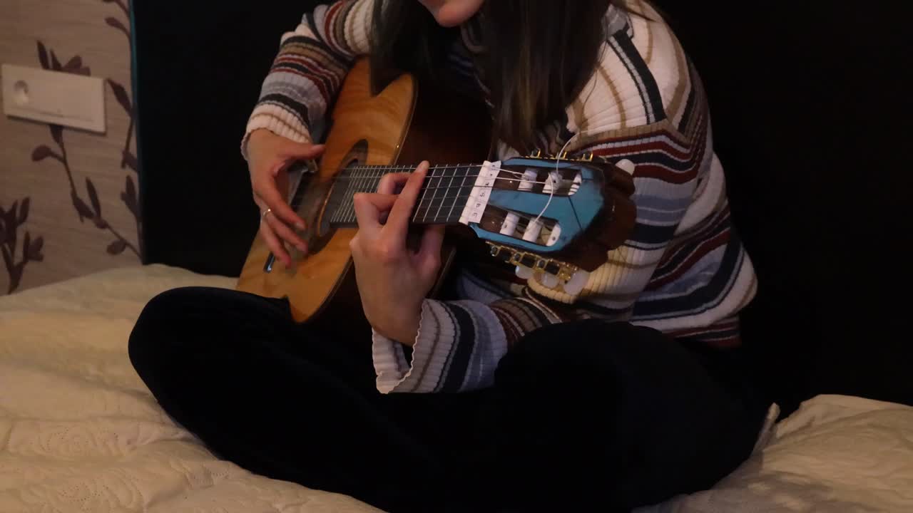 chica de cerca practicando guitarra en la cama