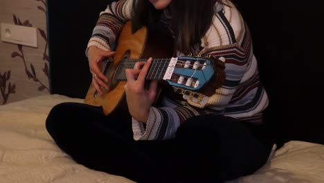 close up girl practicing guitar on the bed