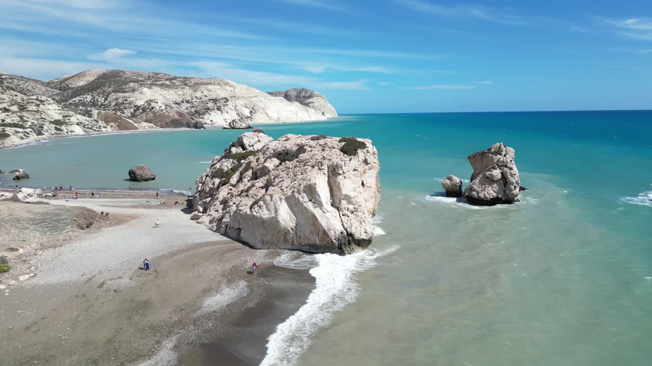 Aerial of Petra tou Romiou beach with iconic sea rocks and turquoise Mediterranean water, establishing overview