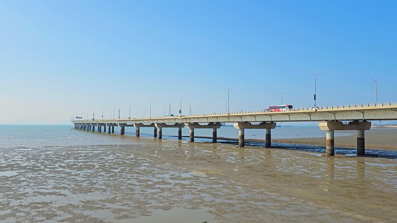 Traffic of Cars on Incheon Bridge which stretches elegantly over tidal flats under a clear blue sky, connecting the mainland to Incheon International Airport with modern infrastructure.
