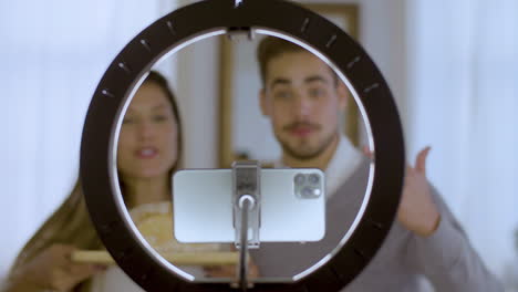 una joven pareja caucásica grabando un video para un vlog de cocina.