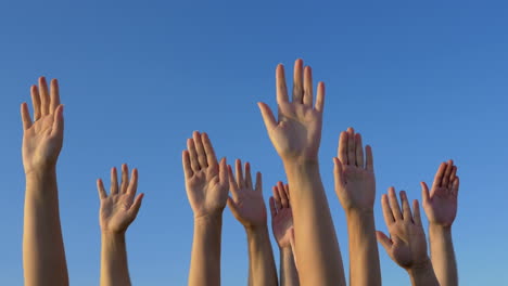 Raised-hands-against-blue-sky