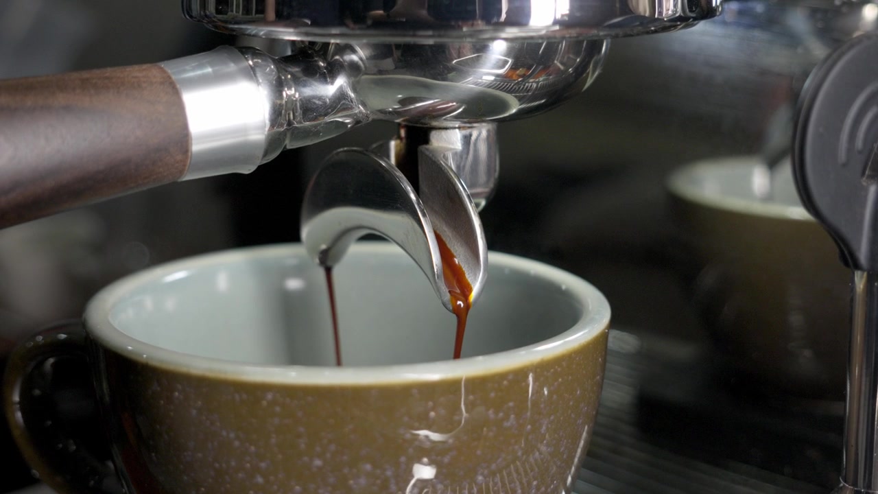 Primo piano di una macchina da caffè espresso, estrazione di caffè espresso che si versa in una tazza.