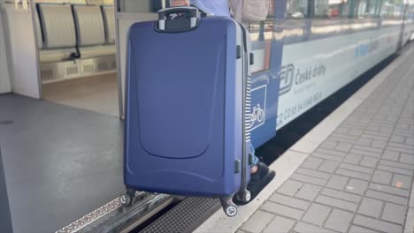 A young traveler with a blue suitcase enters a train car. Traveling by railways