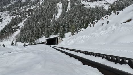 swiss alpine rail road tracks leading to the train tunnel