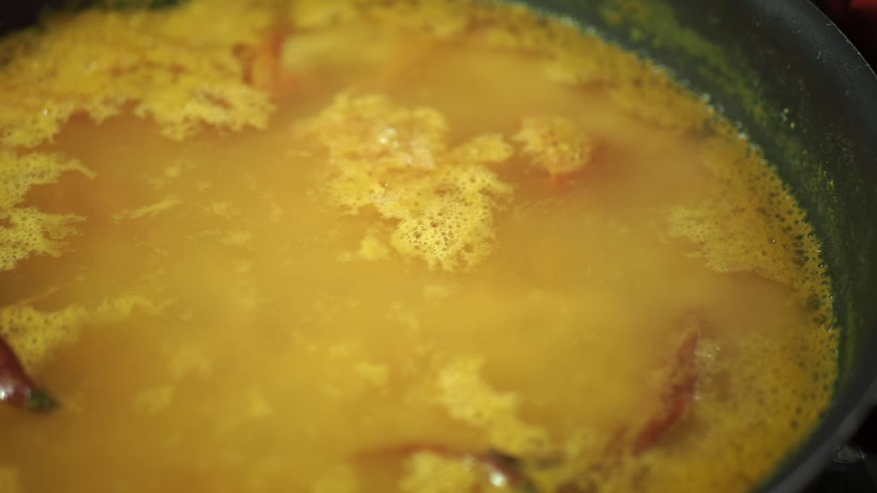 cerca de una olla de sopa amarilla con verduras y especias
