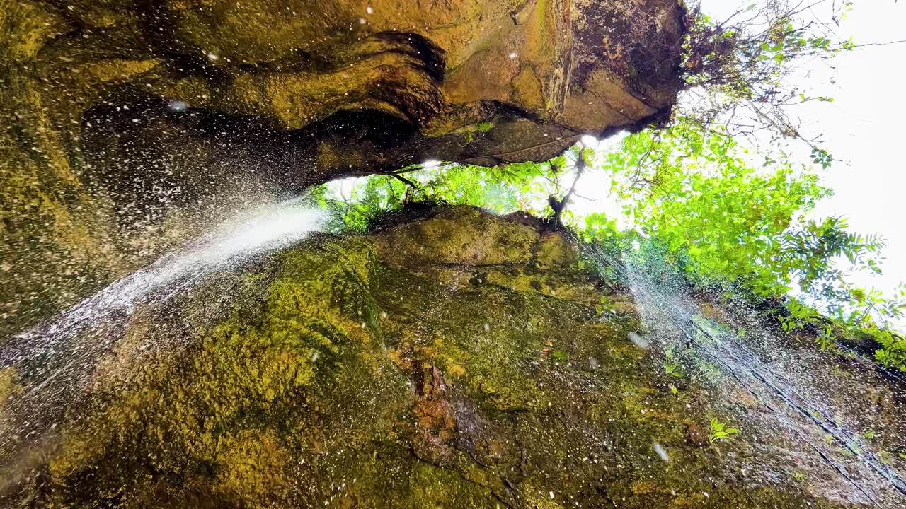 Water fall from a crack in a cliff directly onto the camera