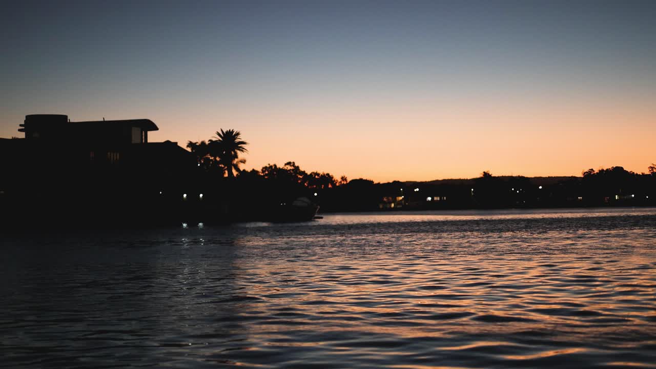 time-lapse de la puesta de sol detrás de las casas frente al mar siluetadas