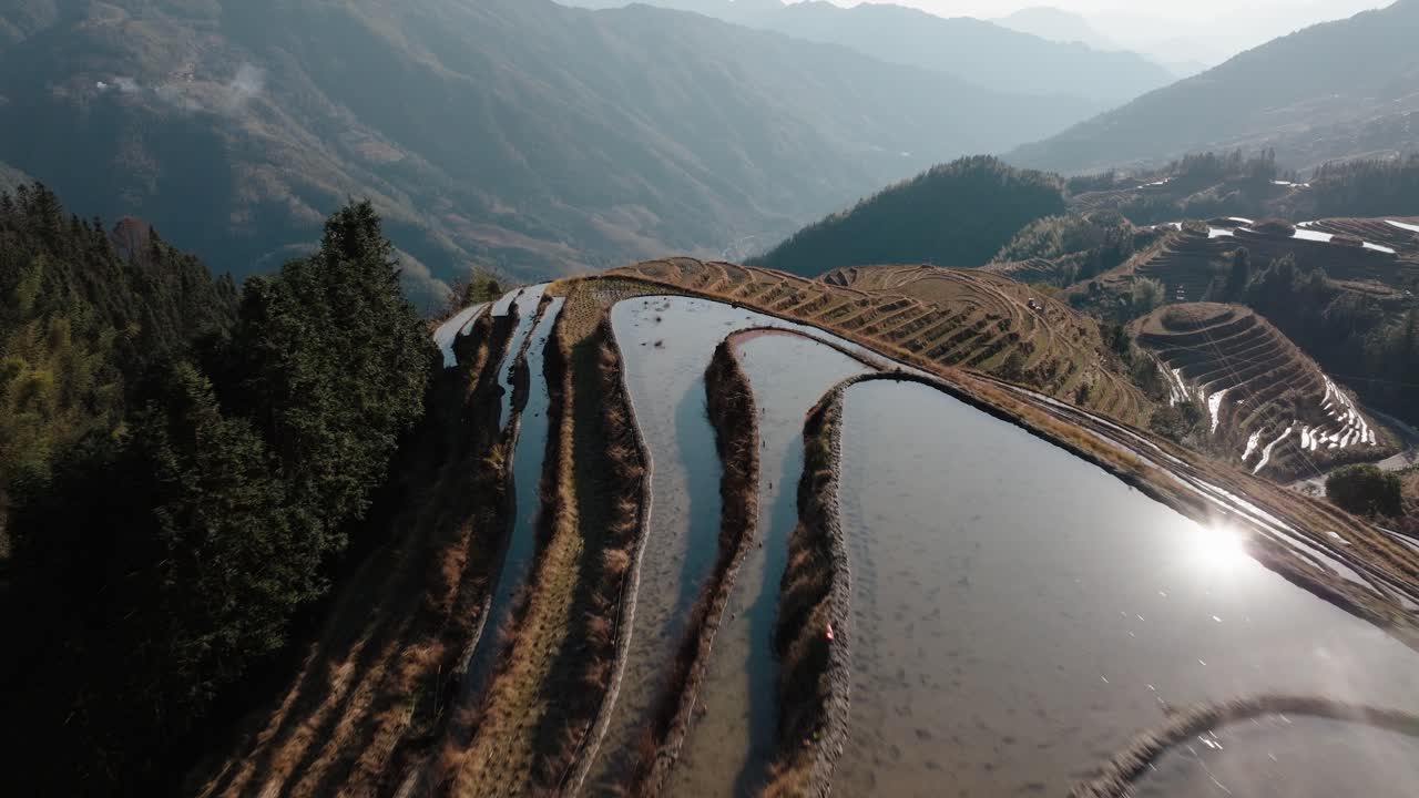 Vista aerea delle risaie terrazzate allagate di Longsheng che riflettono la luce del sole vicino a Guilin, Guangxi, Cina