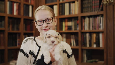 two schoolchildren in the library are a girl and a puppy with glasses. favorite pets and education