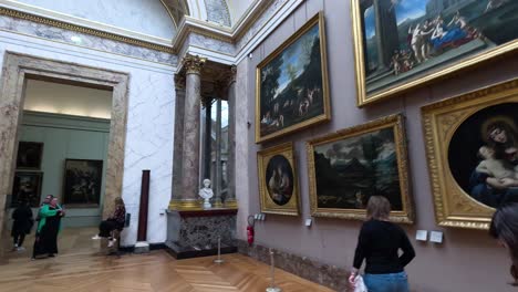 visitors exploring paintings in the louvre museum