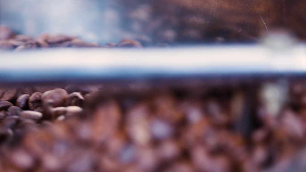 granos de café marrones en un tostador de café movidos