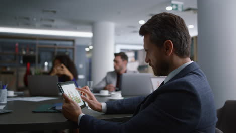 Serious-worker-using-tablet-analyze-data.-Diverse-business-colleagues-on-meeting