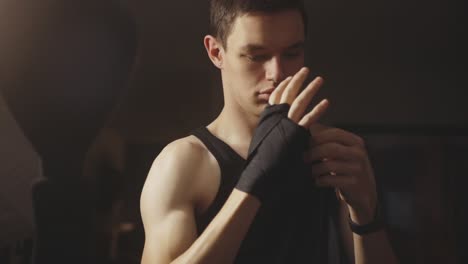 caucasian boxer wrapping hand with black bandage