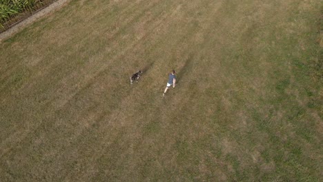 hombre siendo perseguido por su perro pastor en el campo verde rural