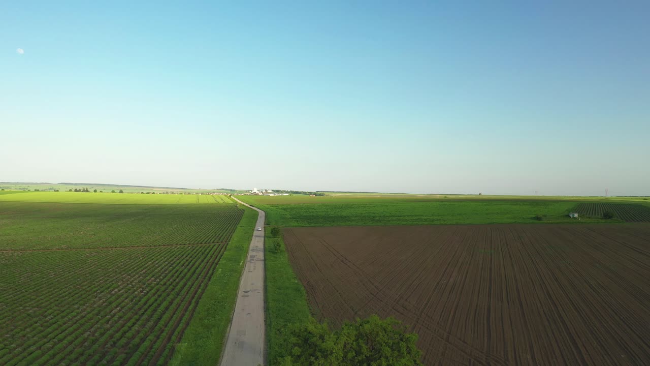 проезжающий мимо автомобиль на пустой дороге в филедах с луной и чистым голубым небом