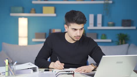 Young-man-looks-working-at-home-focused-on-laptop.