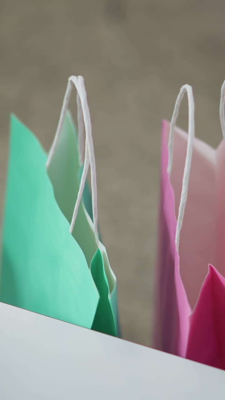 bolsas de compras rosas y verdes brillantes colocadas cuidadosamente en una silla con vista parcial de una mesa en un entorno interior moderno, mostrando un vibrante contraste de colores y simplicidad