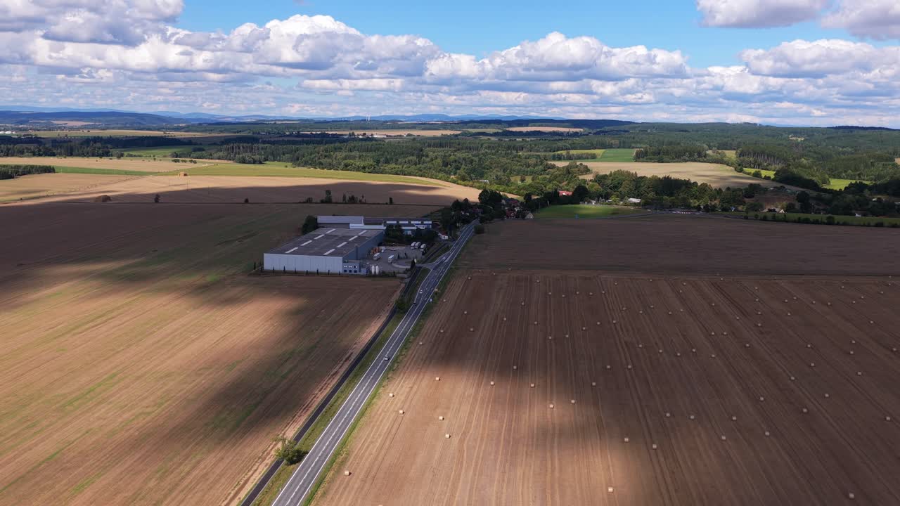 Drone view of a factory surrounded by fields with straw bales. Summer in a rural landscape