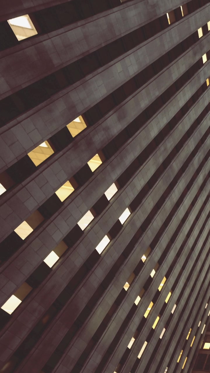 Striking diagonal lines create a modern facade with glowing window reflections