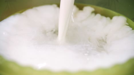 la leche se vierte en un cuenco verde
