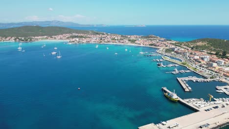 Puerto-De-Golfo-Aranci-Y-Ciudad-Costera-En-Cerdeña,-Italia---Avance-Aéreo-4k