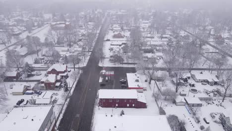 Cozy-iconic-American-town-of-residential-buildings-during-snowfall,-aerial-view