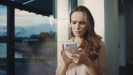 Happy woman looking mobile phone near. Smiling woman scrolling smartphone.