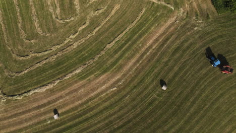 Top-view-overhead-of-tractor-harvesting-field-with-straw-harvester,-Oronoco