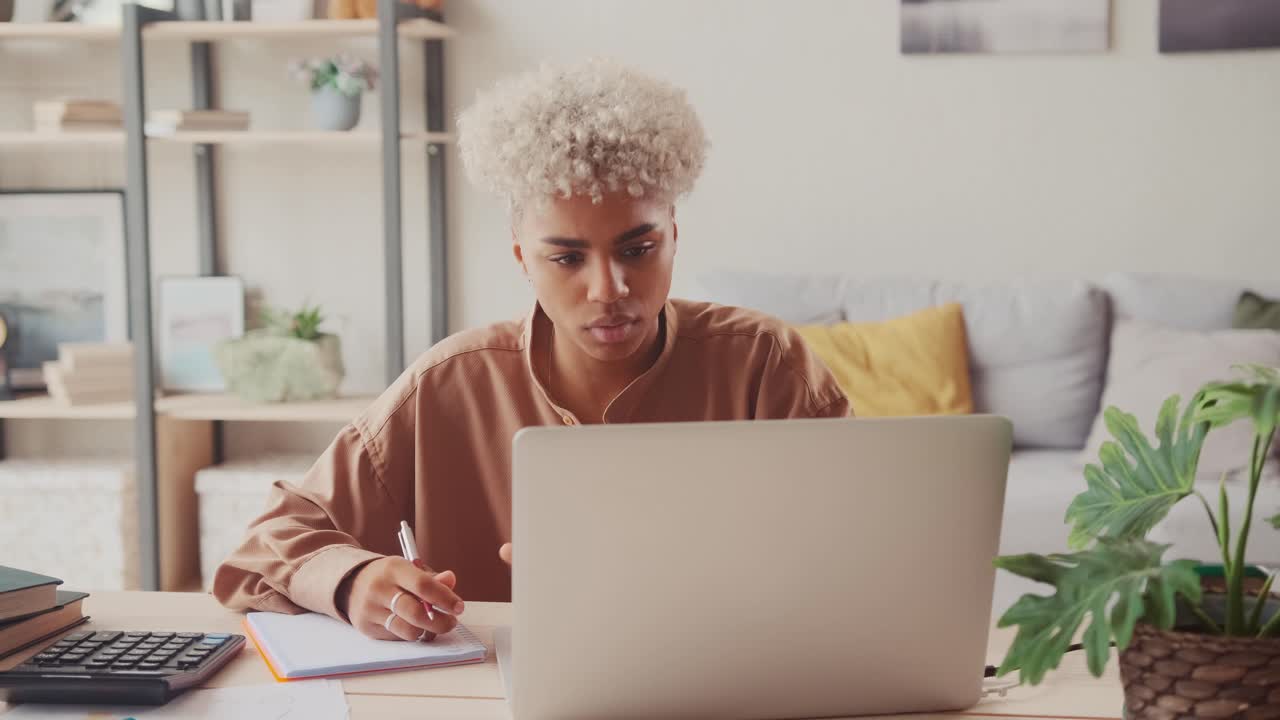 Young african woman with many debts feeling stressed calculating finances