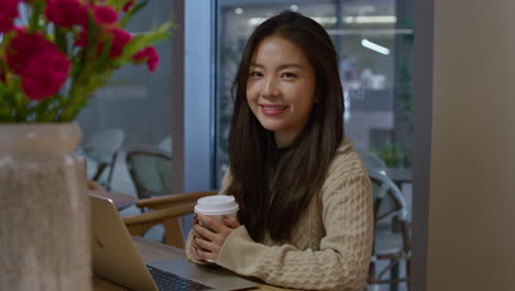 Young-pretty-Asian-woman-smiles-on-camera-in-cafe