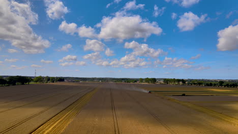 vastas tierras de cultivo en la ciudad de puck en polonia con un tractor agrícola cosechando cultivos en un clima soleado - drone aéreo, tiro panorámico