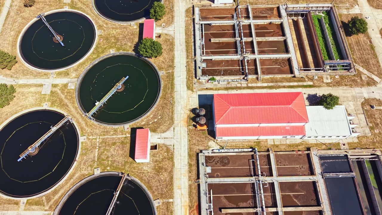 Water treatment facility seen from above with large tanks and buildings next to each other during daylight hours