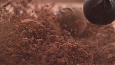 chocolate truffles falling into chocolate powder in super slow motion.